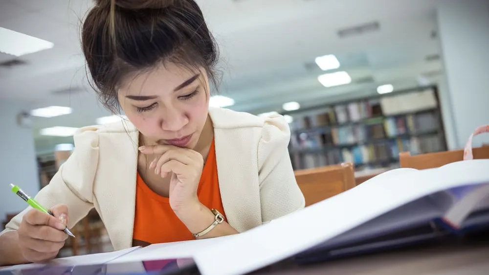 student working on college essay in library