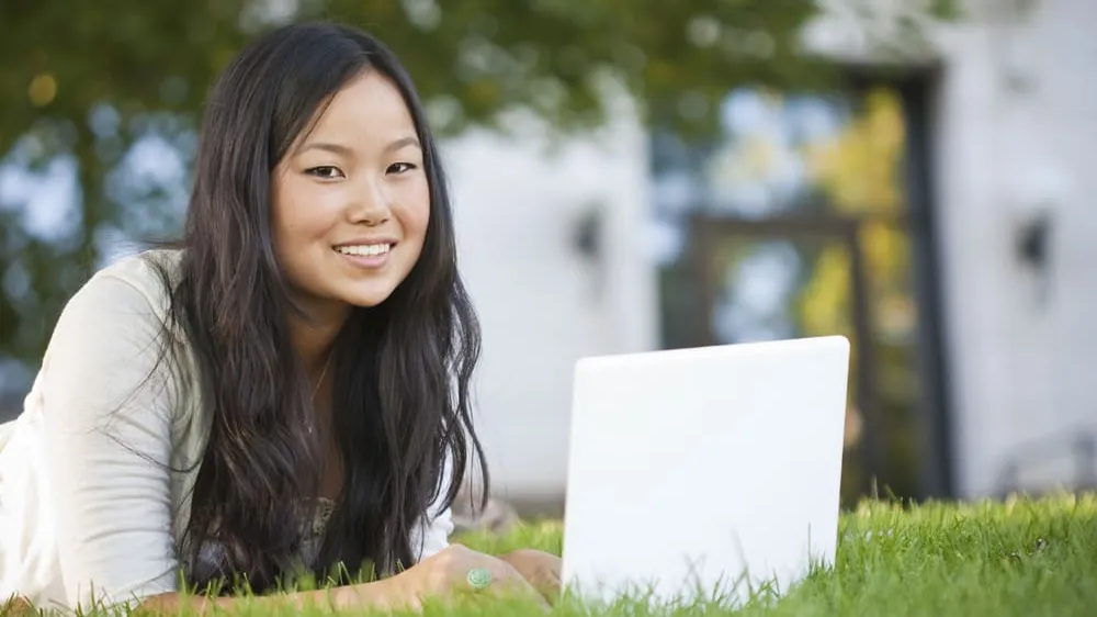 student with laptop on grass